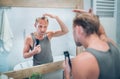 Man looking at bathroom mirror and thinking about his new style haircut analyzing hairs holding electric rechargeable Trimmer. Royalty Free Stock Photo