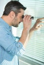 man looking through binoculars at window blind Royalty Free Stock Photo