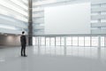 Man looking at a blank white banner in a large bright hall, mock Royalty Free Stock Photo