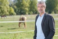 Man looking at camera next to horse fields