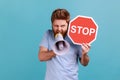 Man looking at camera, screaming in loud speaker, holding red stop sign and megaphone in his hands. Royalty Free Stock Photo