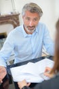 Man looking doubtfully at lady passing him paperwork Royalty Free Stock Photo