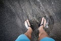 Man looking down at feet and sandals on volcanic black sand beac Royalty Free Stock Photo