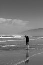 Man looking down standing in front of the ocean in black and white