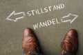 Man looking down at the words Stillstand and Wandel (stagnancy change in German) Royalty Free Stock Photo