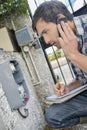 Man looking at exterior electrical box on telephone taking notes