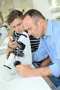 Man looking into eyepiece microscope Royalty Free Stock Photo