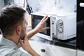 Man Looking At Fire Coming From Microwave Oven Royalty Free Stock Photo