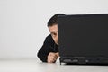 Man looking and hiding behind laptop