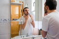 Man looking at himself in a mirror in the bathroom. He is shaving his beard Royalty Free Stock Photo