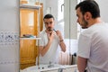 Man looking at himself in a mirror in the bathroom. He is shaving his beard Royalty Free Stock Photo