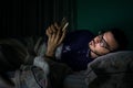 Man looking his mobile phone in the bed at night