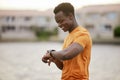 A man looking at his watch and smiling. An African America man in sportswear waiting and smiling at his smartwatch.