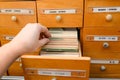 A man is looking for information in a file cabinet. Old wooden card catalog with one open drawer. Database concept