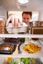 Man Looking Inside Fridge Filled With Food And Choosing Eggs