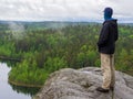 Man looking at the lake and forest. standing on mossy rock. Scandinavian landscape with lake clouds and autumn forest