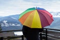 Man looking at mountain panorama holding rainbow colored umbrella on foggy rainy day in autumn Royalty Free Stock Photo