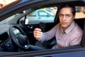 Man looking out from car window and holding a car alarm key