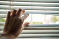 Man is looking out through jalousie or blinds. Privacy concept