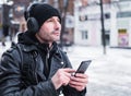 Man looking for a place using GPS map in smartphone. He lost in unknown city. he is dressed in a leather jacket, hat and Royalty Free Stock Photo