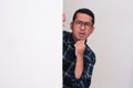 A man looking something from behind white wall with confused expression Royalty Free Stock Photo