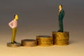 Man looking to business man standing on top of increasing piles of gold coins. Business career concept