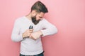 Man is looking to his armpits and smelling the smell that goes from it. Also he is holding a deodorant. Isolated on pink Royalty Free Stock Photo