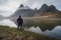 Man looking towards the beautiful mountains of Eystrahorn which reflects in the water. Royalty Free Stock Photo