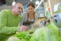 Man looking at vegetables with shop asistant