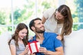 Man looking at wife while holding gift with daughter Royalty Free Stock Photo