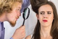 Man looking at woman hair through magnifer Royalty Free Stock Photo