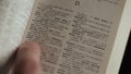 Man looking for word by finger in English explanatory Dictionary