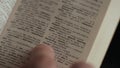 Man looking for word by finger in English explanatory Dictionary