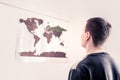 Man looking at a world map on the wall. Thinking about the changing environment, uncertain future or worldwide problems.