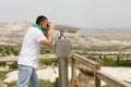 A man looks through binoculars, enjoying a beautiful view from a high mountain Royalty Free Stock Photo