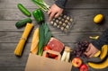 Man looks brown paper bag full of different healthy food