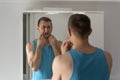 Man looks disgruntled at his reflection in mirror in morning in bathroom. Mens facial skin care and shaving Royalty Free Stock Photo