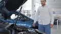 Man looks at the engine compartment of the car at the dealership