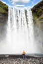 A man looks at the greatness of water jets in a waterfall Skogafoss in Iceland. Exotic countries. Amazing places Royalty Free Stock Photo