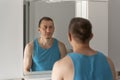 Man looks at himself in bathroom mirror. View over the shoulder. Morning routine. Sleepy tired man in bathroom Royalty Free Stock Photo