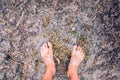 Man looks at his feet submerged in the water of a river on the pebbles