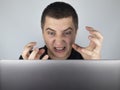 The man looks at the laptop, gets angry and annoyed about what he saw there. Expressing emotions and reacting to what you see on Royalty Free Stock Photo