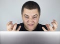 The man looks at the laptop, gets angry and annoyed about what he saw there. Expressing emotions and reacting to what you see on Royalty Free Stock Photo