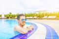 A man looks out of the pool, hanging on the railing.