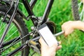 A man looks into the phone, repairing a mountain bike on a forest road. Repair work, mechanic. Royalty Free Stock Photo