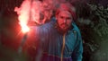 Man lost in the forest holding red burning signal flare to draw attention. Stock footage. Male wearing blue jacket and