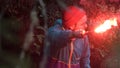 Man lost in the forest holding red burning signal flare to draw attention. Stock footage. Male wearing blue jacket and