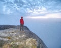 Man lost in thick mist rocks. Hiker climbed up alone to exposed summit