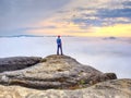 Man lost in thick mist rocks. Hiker climbed up alone to exposed summit