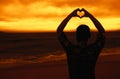 Man in love forming heart at beach at sunset Royalty Free Stock Photo